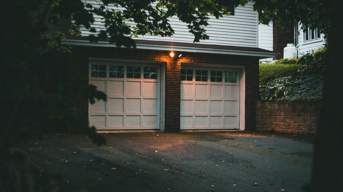 Two white garage doors on a brick home at night with no visible way to cool a garage diy style