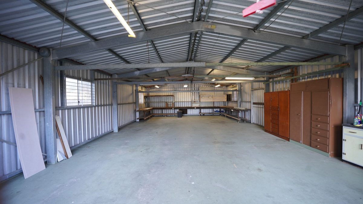 Empty metal garage interior with corrugated walls, concrete floor, and workbenches ready for a project to heat your garage diy