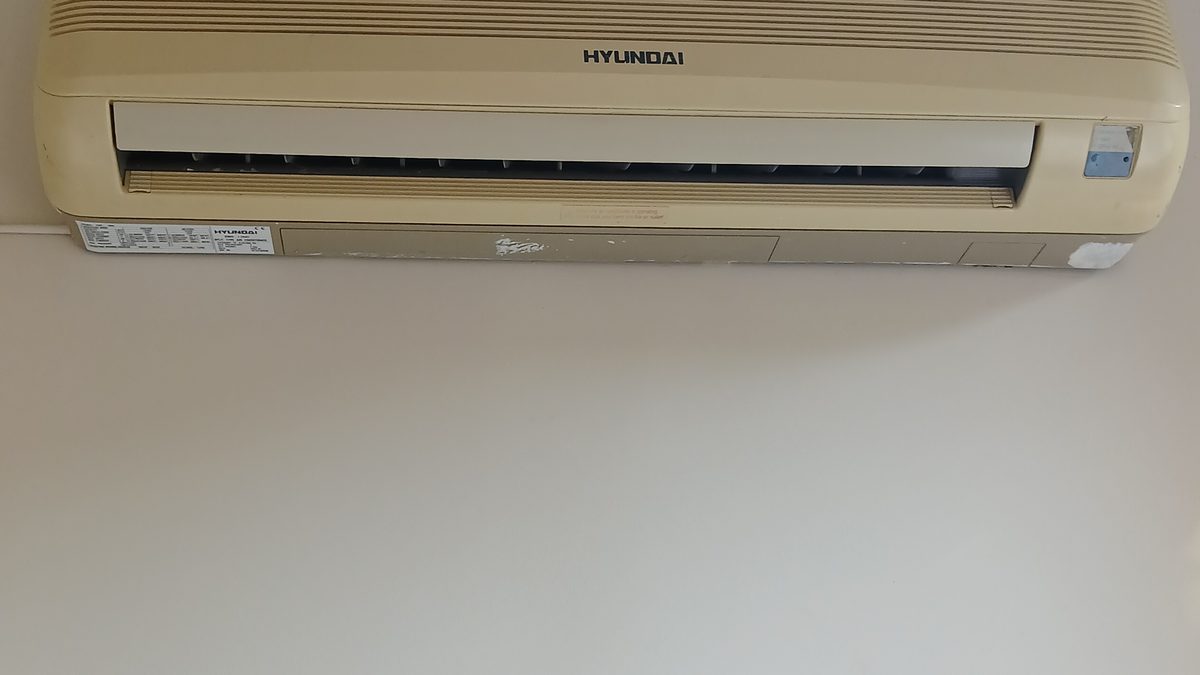 Beige Hyundai wall-mounted mini split indoor unit high on a white wall, a project to install a mini split yourself