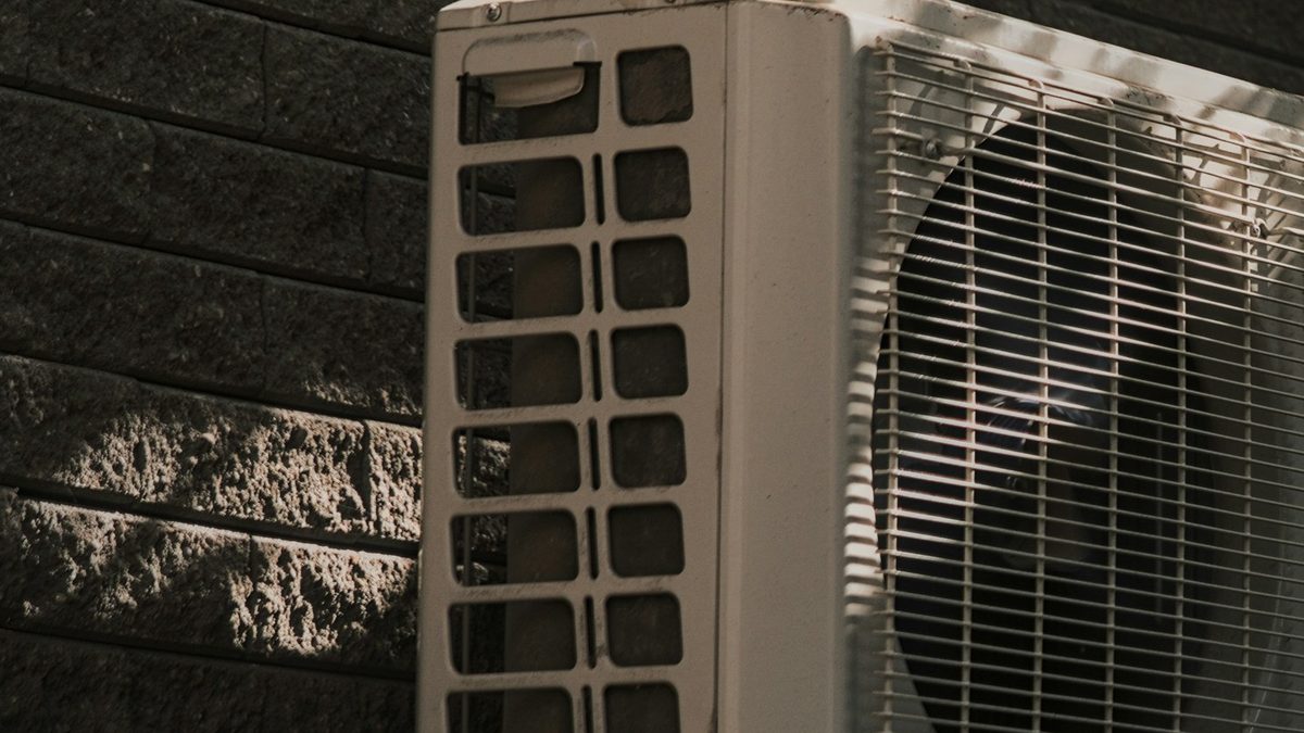 Outdoor condenser unit on concrete base beside a dark brick wall, relevant for an install mini split pole barn guide