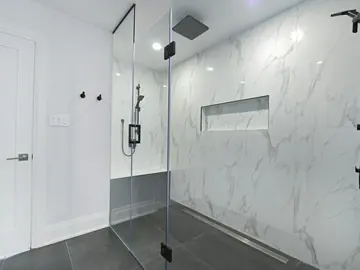 Remodeled bathroom with a glass walk-in shower and marble tile