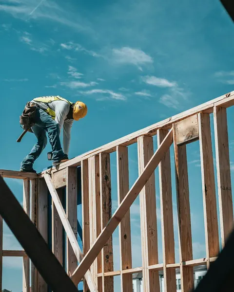Builder standing on a wood wall frame, checking his work